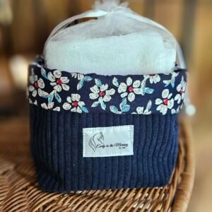 Corbeille artisanale cousue à la main en velours côtelé bleu, avec une bordure en coton fleuri aux petites fleurs rouges et blanches. Elle est accompagnée de 8 carrés démaquillants lavables, composés d’un côté en coton éponge bambou tout doux et d’un côté fleuri assorti. Une création pratique, délicate et éco-responsable pour organiser une routine beauté plus durable.