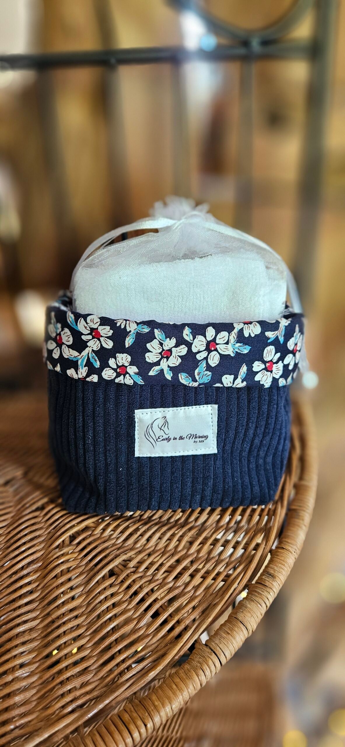 Corbeille artisanale cousue à la main en velours côtelé bleu, avec une bordure en coton fleuri aux petites fleurs rouges et blanches. Elle est accompagnée de 8 carrés démaquillants lavables, composés d’un côté en coton éponge bambou tout doux et d’un côté fleuri assorti. Une création pratique, délicate et éco-responsable pour organiser une routine beauté plus durable.
