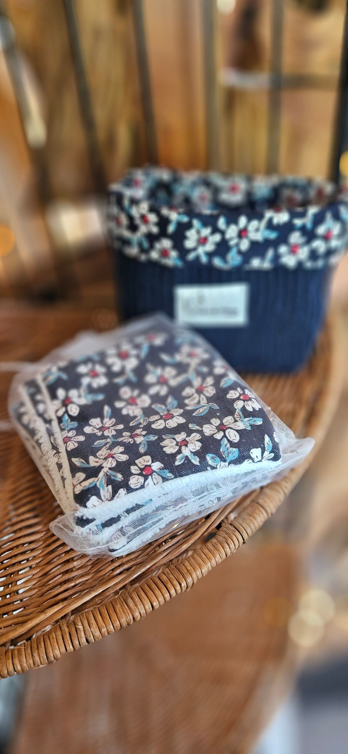 Corbeille artisanale cousue à la main en velours côtelé bleu, avec une bordure en coton fleuri aux petites fleurs rouges et blanches. Elle est accompagnée de 8 carrés démaquillants lavables, composés d’un côté en coton éponge bambou tout doux et d’un côté fleuri assorti. Une création pratique, délicate et éco-responsable pour organiser une routine beauté plus durable.